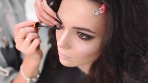 Make-up-Künstler malt Wimpern, Schöne sexy Frau im Schönheitssalon, Hübsches Mädchen macht Make-up