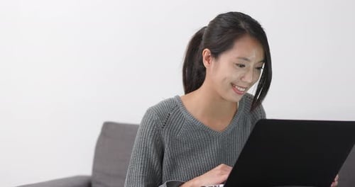 Woman Using Laptop Computer on Couch at Home