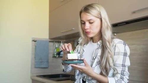 Woman Enjoys Cake Slice in Modern Kitchen