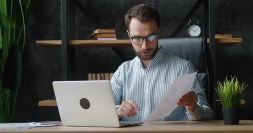 Man works at computer with documents in office
