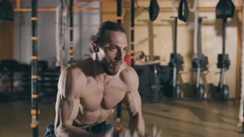 Junger Mann trainiert mit Battle Ropes