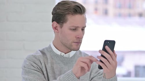 Man Uses Smartphone in Bright Indoor Setting