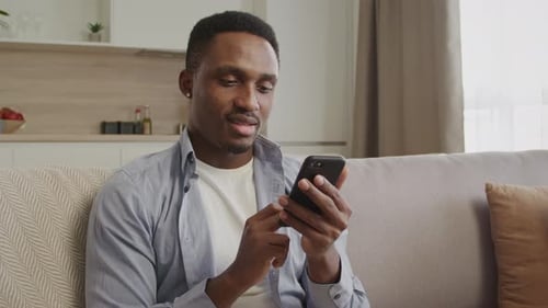 Young Adult Using Phone on Couch Indoors