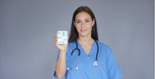 Woman Doctor in Scrubs Holding Blister Pack of Pills