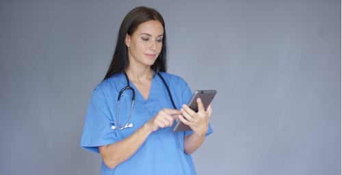 Young Female Doctor In Scrubs Using a Tablet