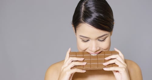 Mujer bonita mordiendo en una barra de chocolate