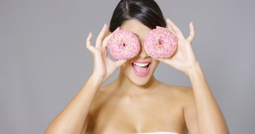 Woman Holds Pink Donuts Up To Eyes