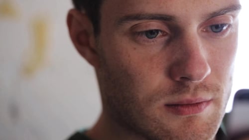 Young Adult Using Mobile Phone Indoors, Close Up