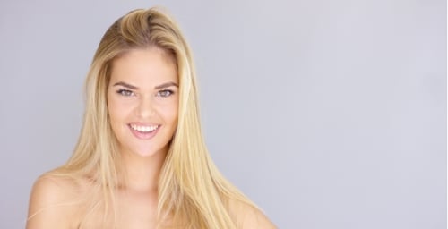 Smiling Woman with Blonde Hair Touching Her Hair