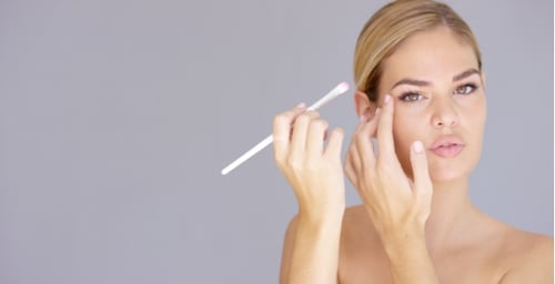 Junge Frau, die Augen-Make-up auf ihr Augenlid aufträgt