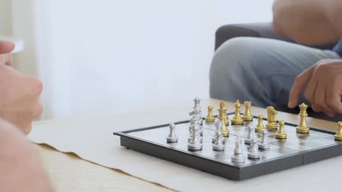 Happy family with senior father playing chess with son together with enjoy on sofa at home.