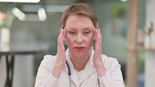 Stressed Female Doctor Touching Temples in Office