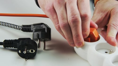 Hands Unplug Orange Electrical Plug From Extension Cord