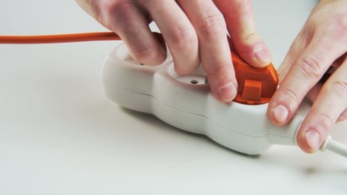Hands Plugging Cords into Power Strip