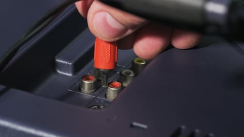 Hand Connects Red RCA Connector to Television