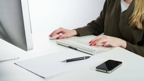 Frau benutzt Maus und tippt auf einer Tastatur