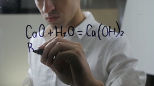 Young Man Writing Chemical Equations on Glass