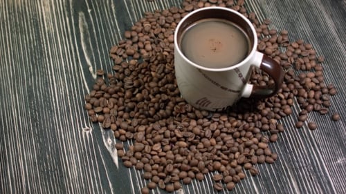 Tasse Kaffee und Getreide auf dem Tisch auf dunklem Hintergrund, duftendes Heißgetränk