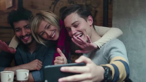 Video calling on phone. Happy friends using mobile phone in cafe