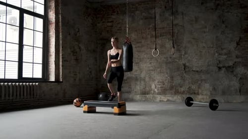 Woman Exercising on Step Platform in Urban Gym