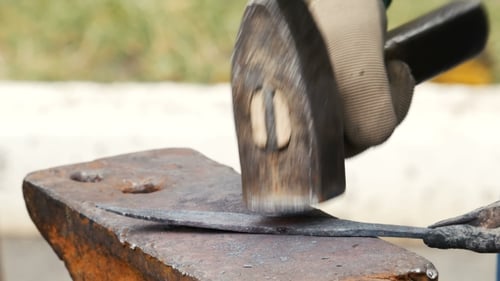 Blacksmith Forging Metal Knife with Hammer on Anvil