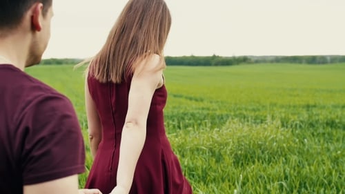 Jeune couple amoureux. Un homme suit sa petite amie, lui tient la main, marche dans un champ