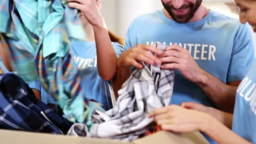 Grupo de voluntarios con ropa en una caja de donación