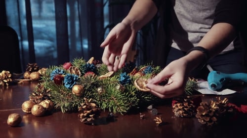 Person Crafting a Christmas Wreath at Home