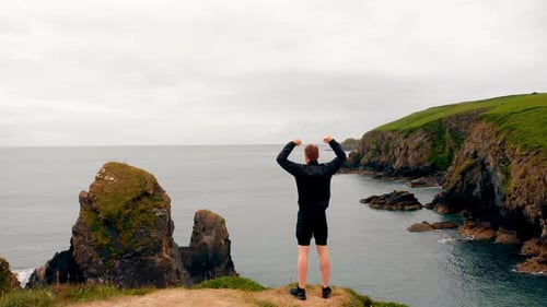 Man standing on cliff on a breezy day 4k