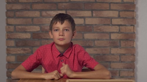 Child Sitting at the Desk Holding Flipchart with Lettering Day Off on the Background Red Brick Wall.