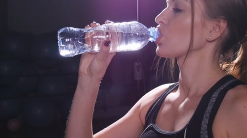 Young Fit Woman Drinking Water at Gym