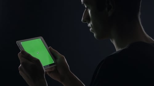 of Man Using Digital Tablet with Green Screen in Dark Room
