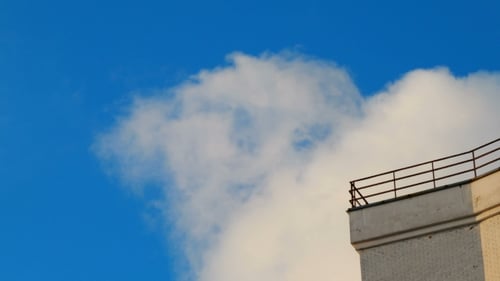 Clip von weißen, flauschigen Wolken über blauem Himmel. und Ecke des Gebäudes. Wunderschöne Wolkenlandschaft.