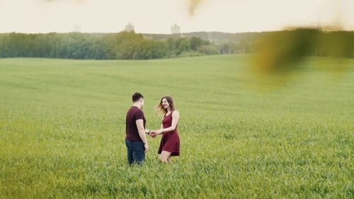 Loving Couple Hug, Standing in a Field. They Smile Happily, Look at Each Other, Hold Hands.