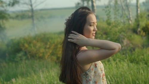 Girl Touches Her Hair and Looks Back in the Foggy Forest
