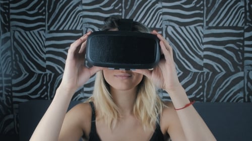 Young Woman Wearing Virtual Reality Headset in Bedroom