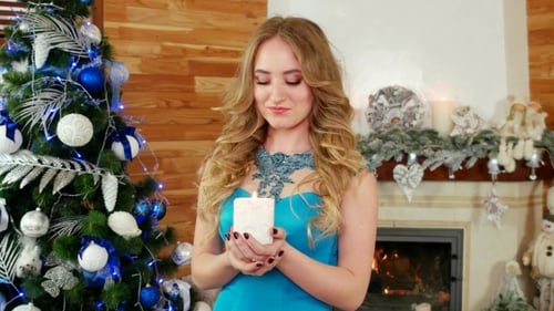 Woman Holding Christmas Candle in Front of Tree