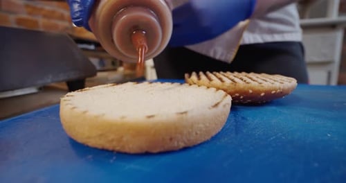 Chef Preparing the Burger, Hand of Man Smears Sauce Fried Burger for a Hamburger. Slow Motion Close