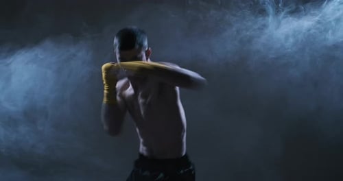 Young Man Shadow Boxing in Smoky Dark Gym