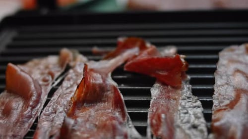 Raw Bacon Cooking on Electric Grill Close Up