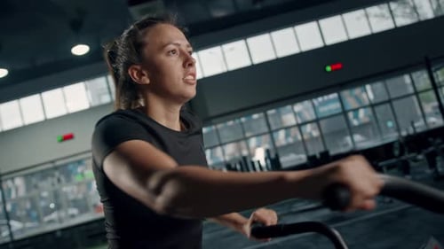Woman Works Out on Bike at Modern Gym