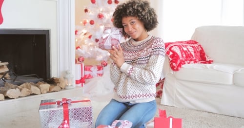 Woman Holding Christmas Gift in Festive Living Room