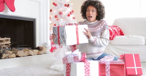 Woman Holding Christmas Gift with Christmas Tree