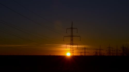 Sonnenuntergang auf dem Hintergrund von Stromleitungen