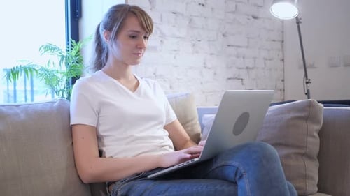 Young Woman Celebrating Success on Laptop at Home