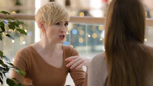 Gros plan femme blonde d'âge moyen avec coupe de cheveux courte parlant bavarder avec une dame méconnaissable