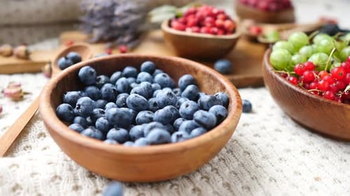 Fresh Blueberries Falling into a Wooden Bowl