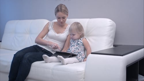Young Adult and Child Using Tablet on Sofa