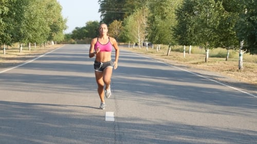 Beautiful Sportswoman Running on a Country Road. Training Outdoors