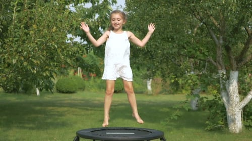 Niña saltando en el trampolín en el jardín
